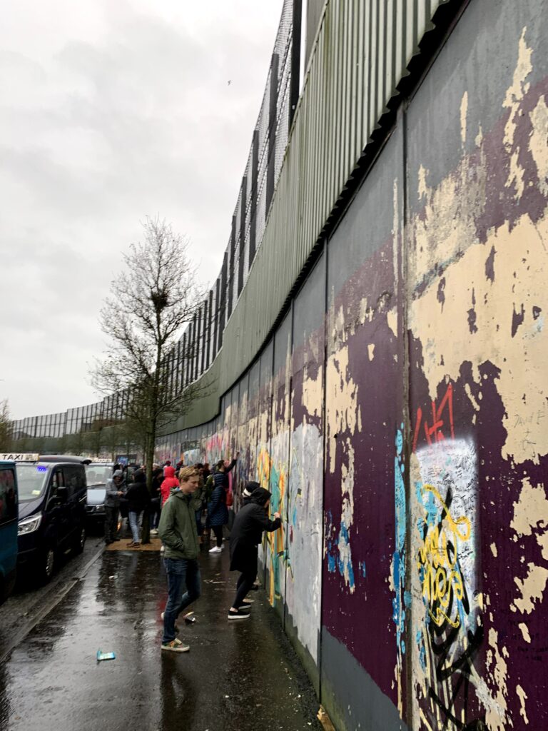 people gathered writing messages on a wall